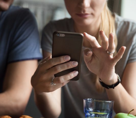 ¿Se debe revisar el celular de la pareja? Pareja discutiendo sobre confianza y privacidad con un celular de fondo