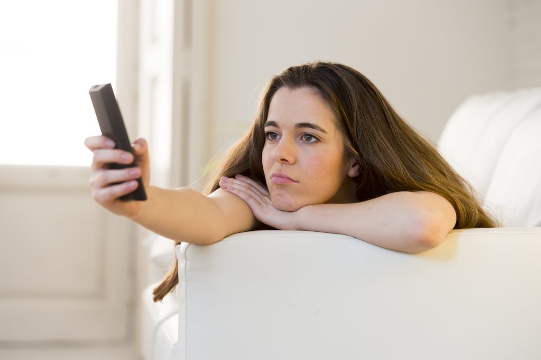 Young,Beautiful,Woman,Lying,At,Her,Apartment,Living,Room,On zapping