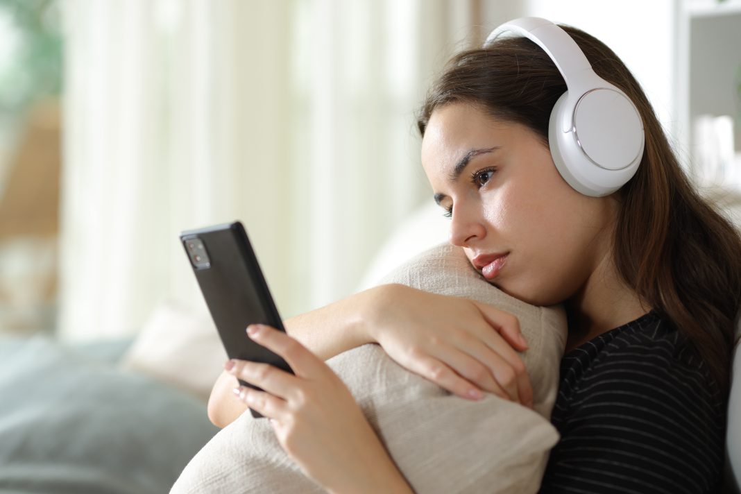 Serious,Woman,Wearing,Headphone,Checking,Mobile,Phone,Sitting,On,A redes