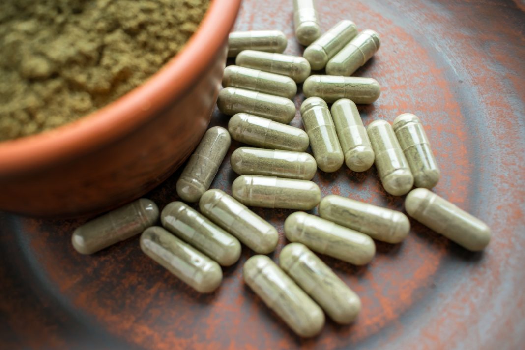Supplement,Kratom,Green,Capsules,And,Powder,On,Brown,Plate.,Herbal drogas
