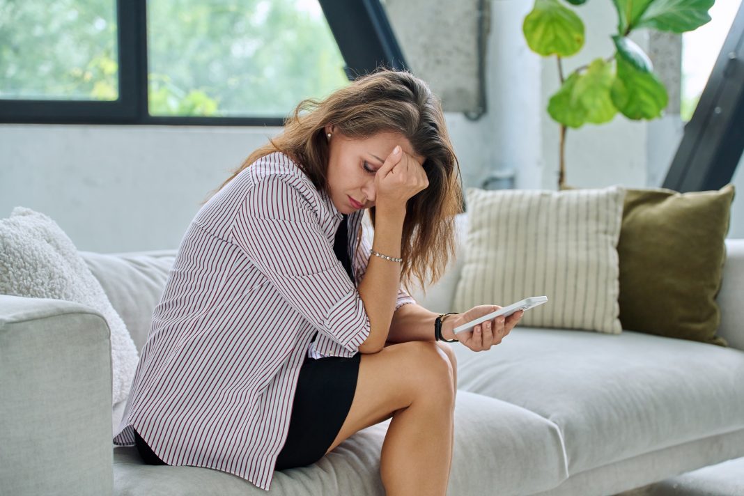 Sad,Serious,Middle,Aged,Woman,With,Smartphone,Sitting,On,Sofa rutina